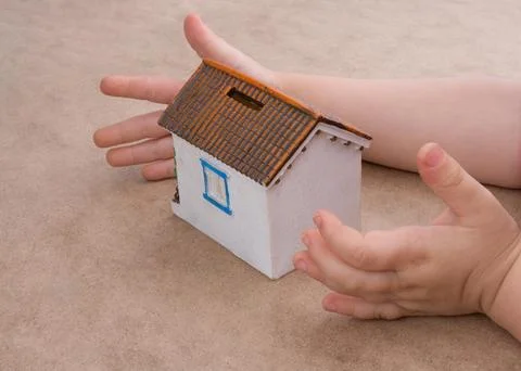 Little model house and a hand on a light brown color background Stockfoto's