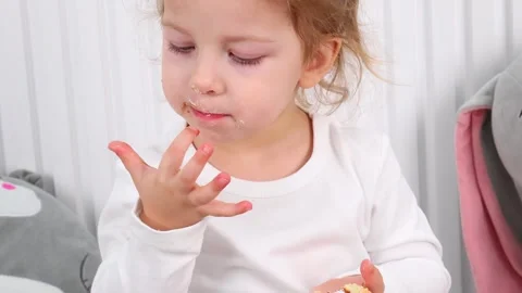 Little one explores flavors while enjoying a delicious treat at home Stock Footage 295357297