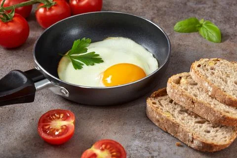 Little pan with a fried egg, bread and cherry tomatoes Stock-Fotos