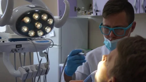 Little patient, dentist using dental drill in modern dental clinic Stock Footage