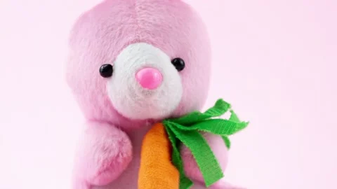 Little pink Easter plush bunny toy with an orange little carrot sits on a pastel Stock Footage 149041365
