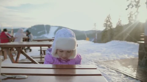 Little plays at the dinner table in the midst of snow-capped mountains. Stock Footage 109413678