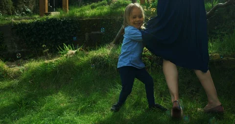 Little preschooler chasing bubbles around his mother on the lawn Stock Footage 130126085