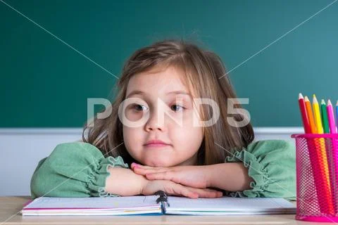 Photograph: Little pretty girl sitting in the classroom at the gray ...