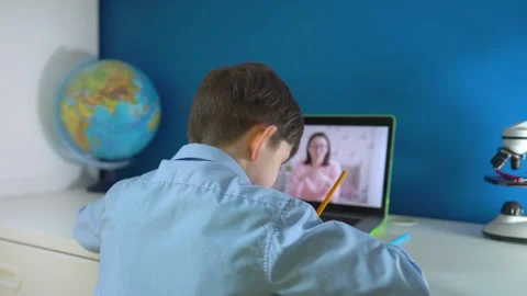 Little primary school boy sit at table at home hold pen take notes on copybook Stock Footage 152879122