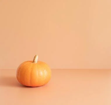 Little pumpkin on a beige background with a copy space. Halloween Stock Photos