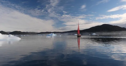 Little red sailboat sailing between icebergs. Stock Footage 100592802