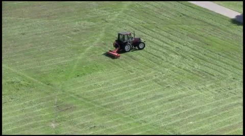 A little red tractor mower mows the grass Stock Footage 10682571