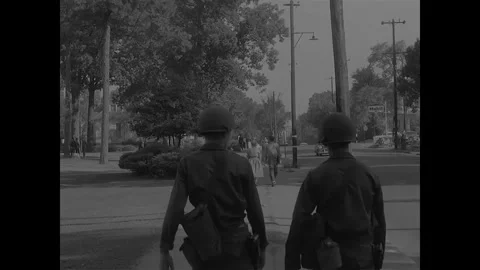 LITTLE ROCK - 1957: Desegregation — Two soldiers walk away toward junction Stock Footage 342230993