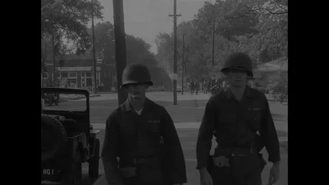 LITTLE ROCK - 1957: Desegregation — Two soldiers approach corner past HQ jeep Video stock 342230998
