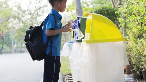 Little school boy keep trash into park bin keep clean in city public park Stock Footage 301371490