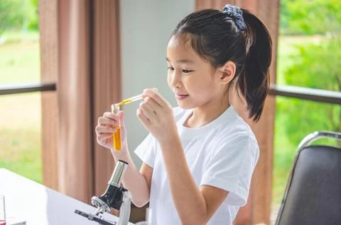 Little scientist looking through a microscope and test tubes filled with ch.. Stock Photos