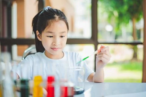 Little scientist looking through a microscope and test tubes filled with ch.. Stock Photos