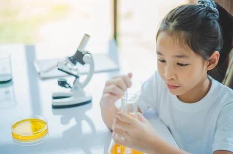 Little scientist looking through a microscope and test tubes filled with ch.. Stock Photos