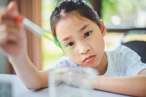 Little scientist looking through a microscope and test tubes filled with ch.. Stock Photos