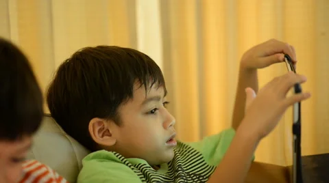 Little sibling boy playing game tablet mobile together Stockbeeldmateriaal 65034905