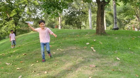 Little sibling boy playing plane paper in the park Stock Footage 62651885