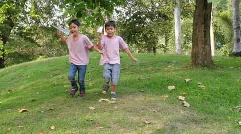 Little sibling boy playing plane paper in the park Stock Footage 62653000