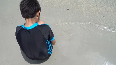 Little sibling boy playing sand on the beach summer time Stockbeeldmateriaal 89754417
