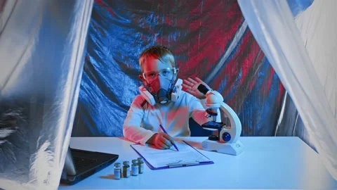 A little sientist with a microscope is writing down the results of his Stock Footage 166025595