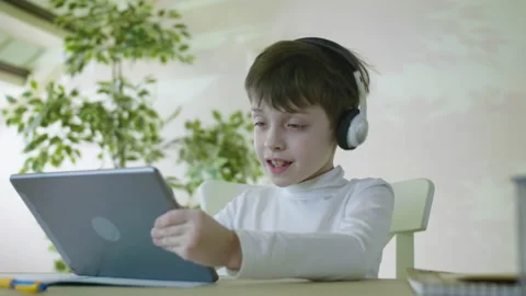 Little Smiling Boy Sitting At The Table Listening To Music And Playing Games On Stock Footage 204771628
