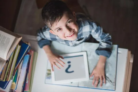 Little smiling boy is using a tablet. Top view. Stock Photos