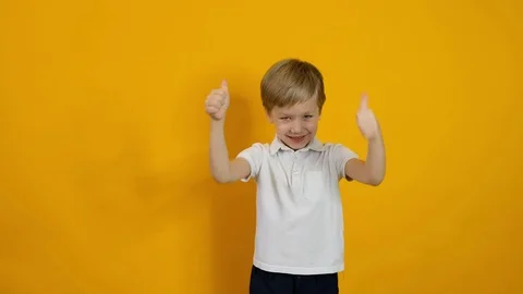 Little smiling five years old boy showing thumb up over yellow background Stock Footage 123781402