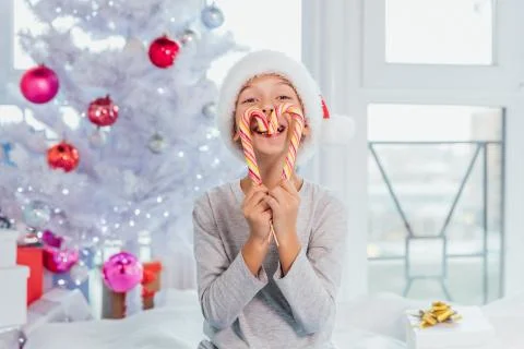 Little sweettooth boy holds delicious candies in front of mouth, looks directly Stock Photos