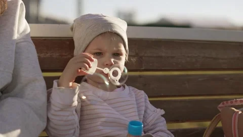 Little toddler blowing soap bubbles outside Stock Footage 335523029
