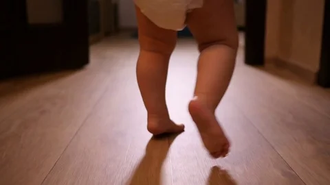 Little toddler legs of a baby child walking on floor at home in slow motion Stock Footage