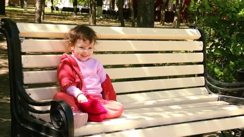 Little two year old child is sitting on the bench and smile. spring afternoon Stock Footage 90265145
