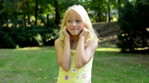 Little upset girl covers her ears with fingers in the park - annoyed Video stock 58502053