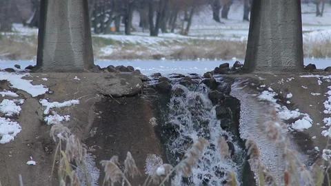 Little waterfall under the bridge on the background of lake at winter wather Stock Footage 89779450