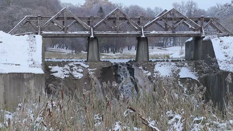 Little waterfall under the bridge on the background of lake and some snowfall Stock Footage 89782088