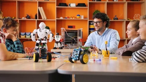 Little white robot posing in front of the kids and their male teacher on the Stock Footage 82481777