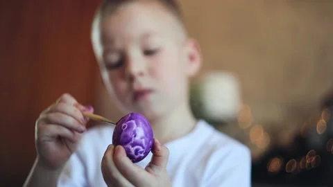 A little white-skinned boy with a diligent face paints an Easter egg.  Easter Eg Stock Footage 150034687