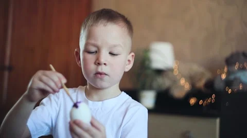 A little white-skinned boy with a diligent face paints an Easter egg.  Easter Eg Stock Footage 150034695
