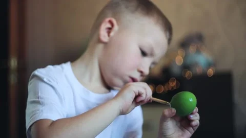 A little white-skinned boy with a diligent face paints an Easter egg.  Easter Eg Stock Footage 150034726