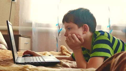 Little young boy using a notebook in a bedroom are playing the bed. boy teen Stock Footage 98383368