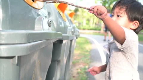 Litttle asian boy collecting garbage and plastic bottles in park Stock Footage 130893484