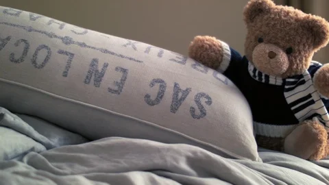 Live Animated Teddy Bear On A Bed Waving Hand By A Pillow 库存影片 117243578