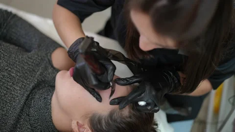 Live camera spinning as concentrated tattoo master filling eyebrow skin with Stock Footage 201927894