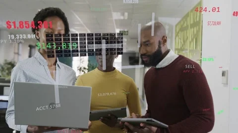 Live data feed updating, team viewing laptop and tablets while finance overlays Stock Footage 332956214