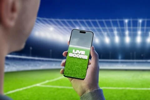 Live score online interface on smart phone in man hand. Stadium in background Foto stock