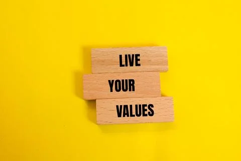 Live your values message written on wooden blocks with yellow background. Con Stock Photos