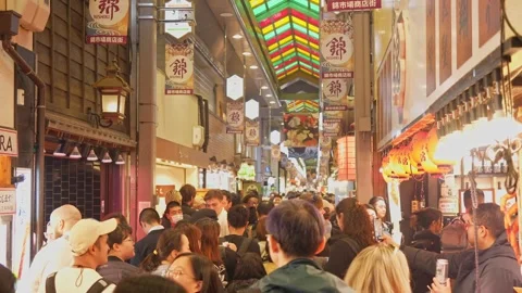 A lively crowd moves through Nishiki Market in Kyoto, exploring a maze of food Stock Footage 302874188