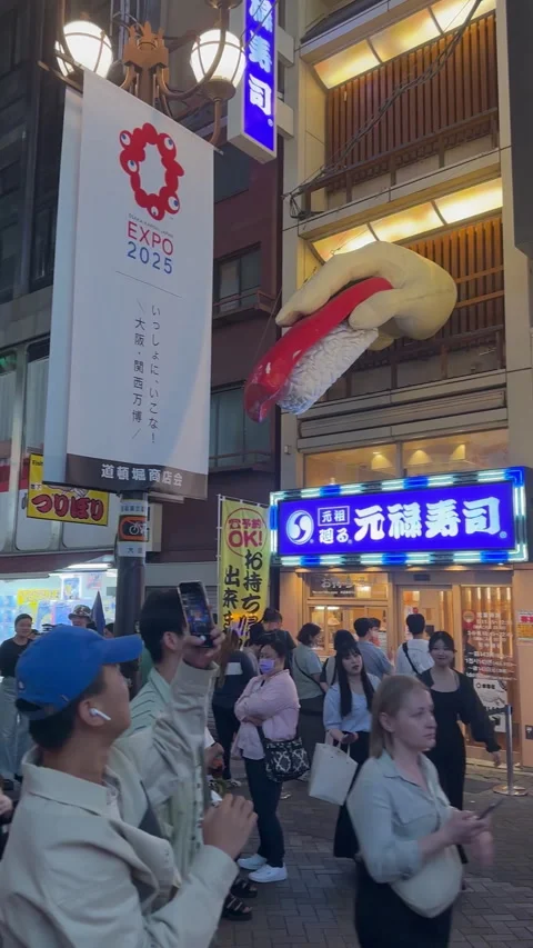 A lively street scene features a distinctive entrance in Osaka Stock Footage 316174815