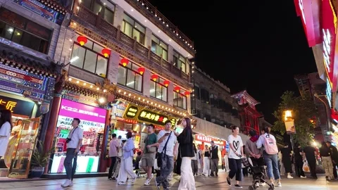 A lively urban street at night, featuring traditional Chinese architecture and Stock Footage 337306053