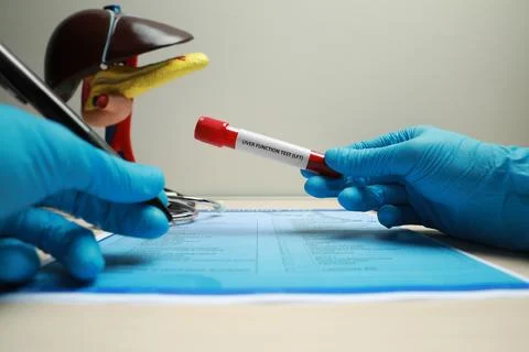 Liver Function Test. Laboratory worker with tube of blood sample filling in.. Stock Photos