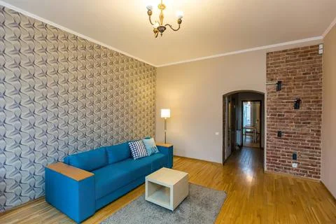 Living room with blue sofa, patterned wall, wooden floor Stock Photos